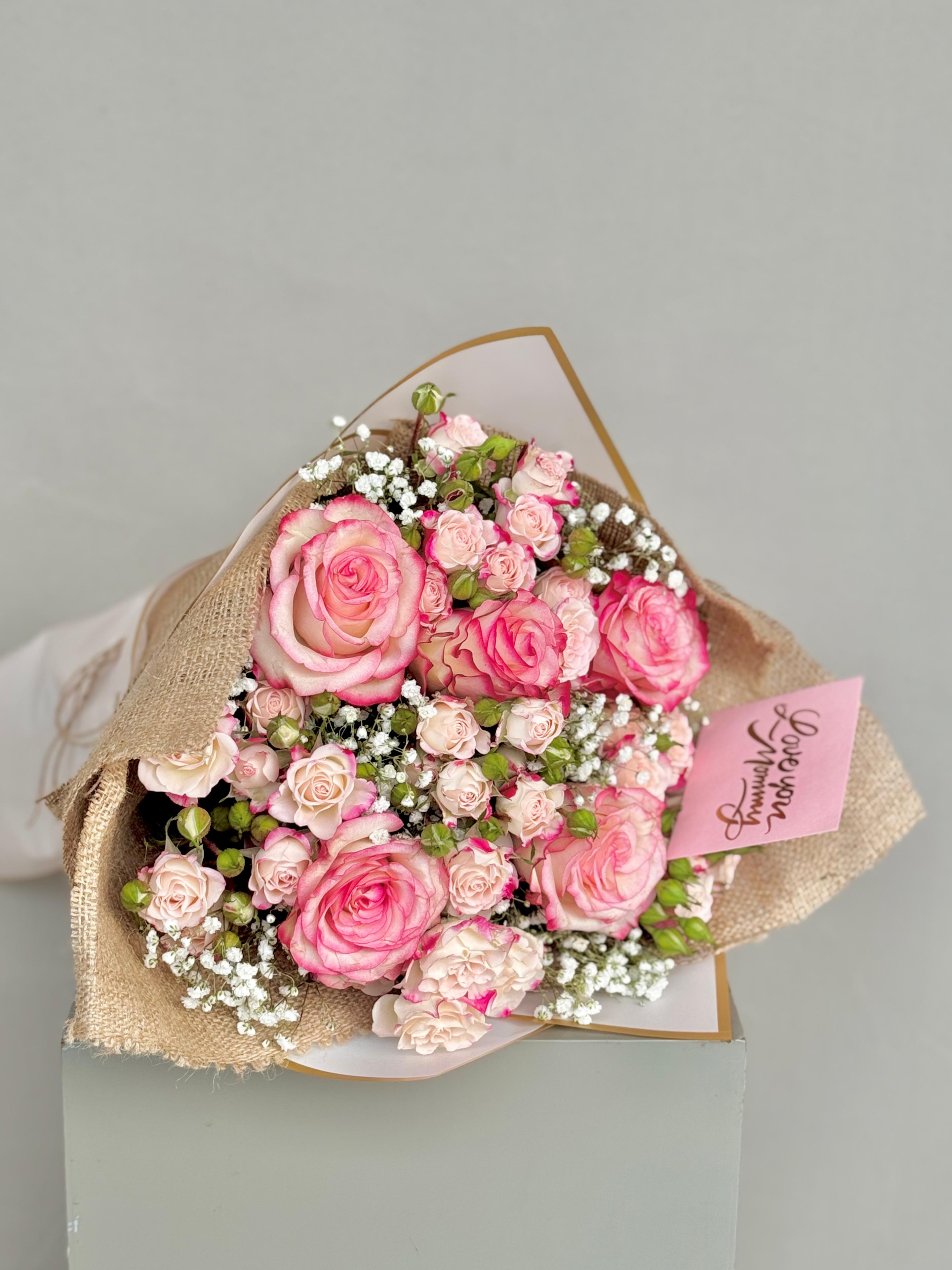 Bouquet of pink roses with a small card on a gray background