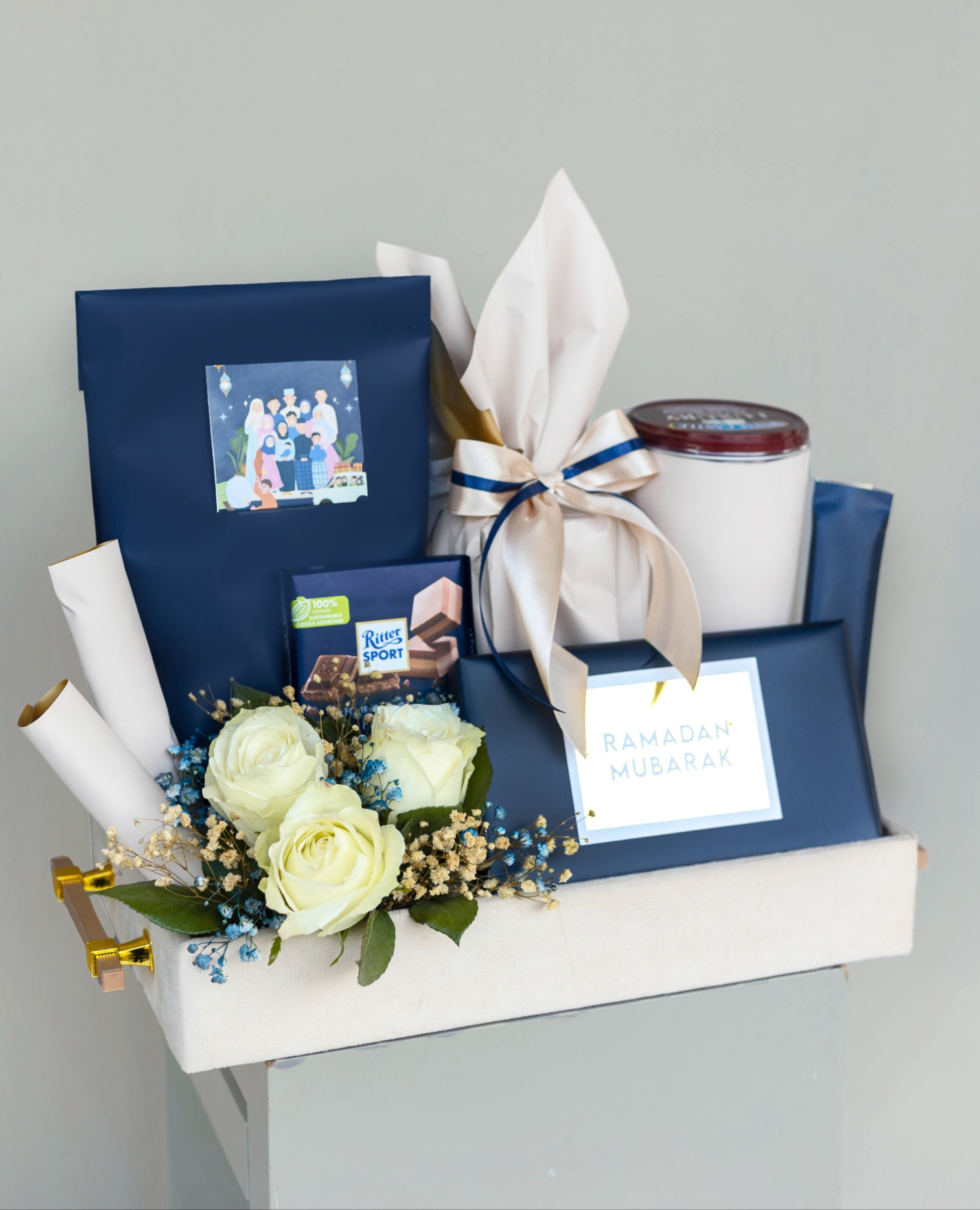 Ramadan or Ramazan gift basket with flowers, candles, and photo albums on a gray background