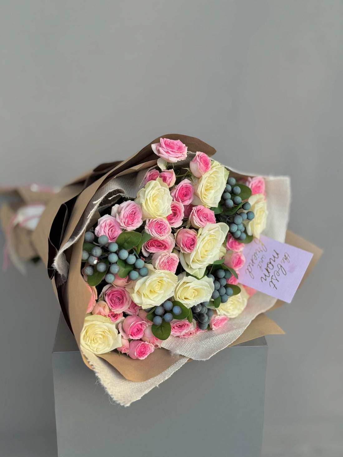 Bouquet of pink and white roses with green berries on a gray background