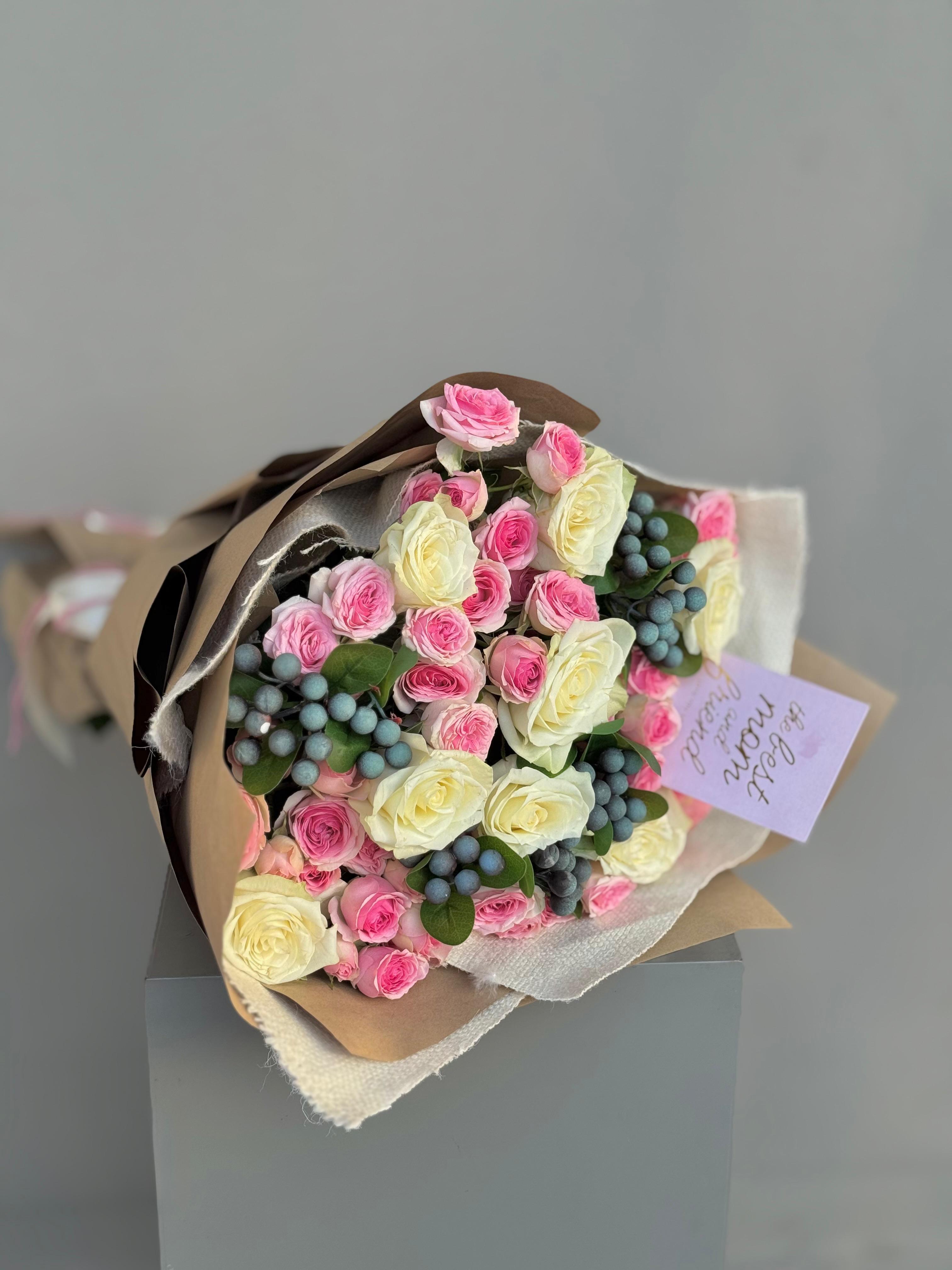 Bouquet of pink and white roses with green berries on a gray background