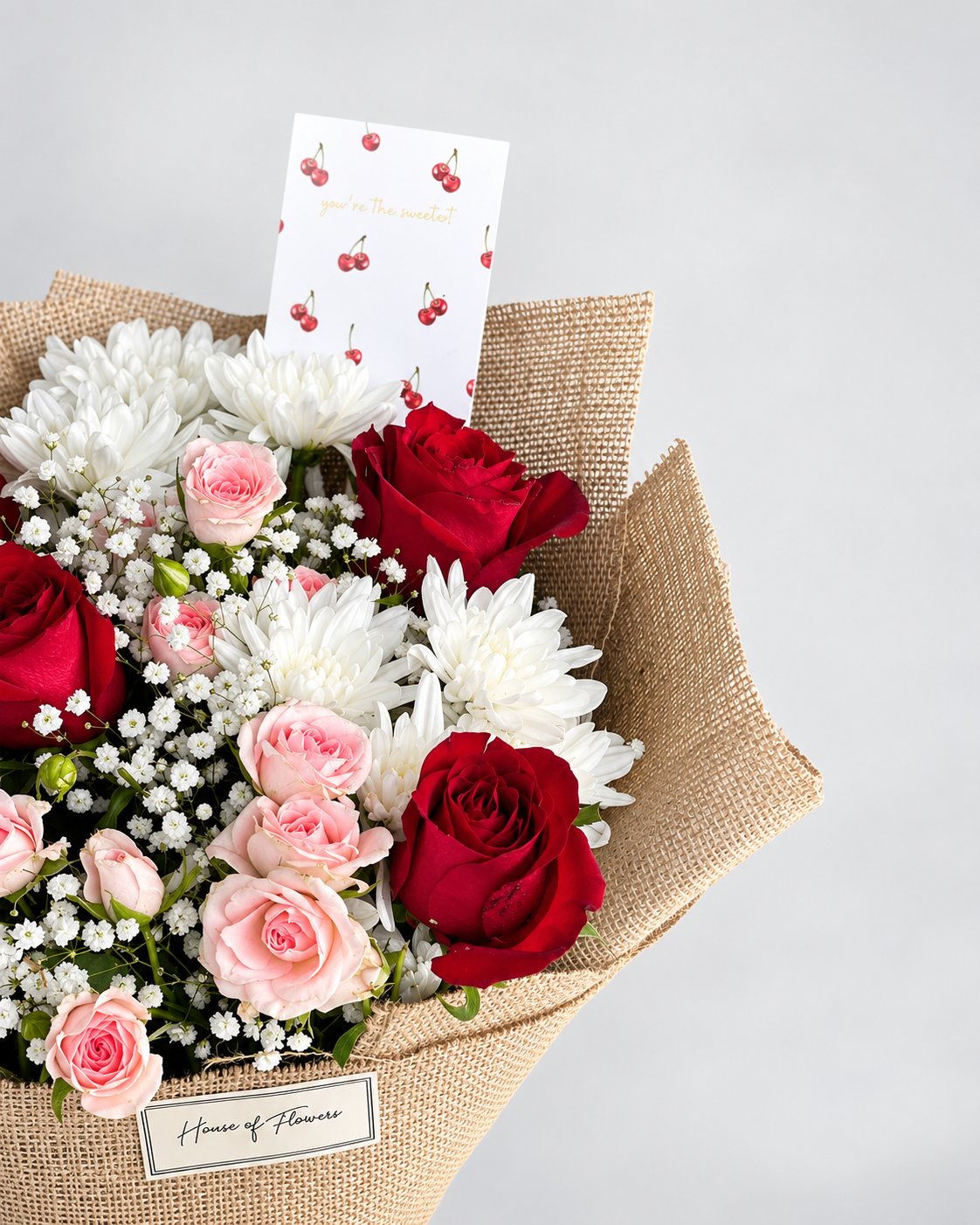 Close-up of the Cherry Blossom bouquet with red and peach roses, chrysanthemums and a cherry-print card