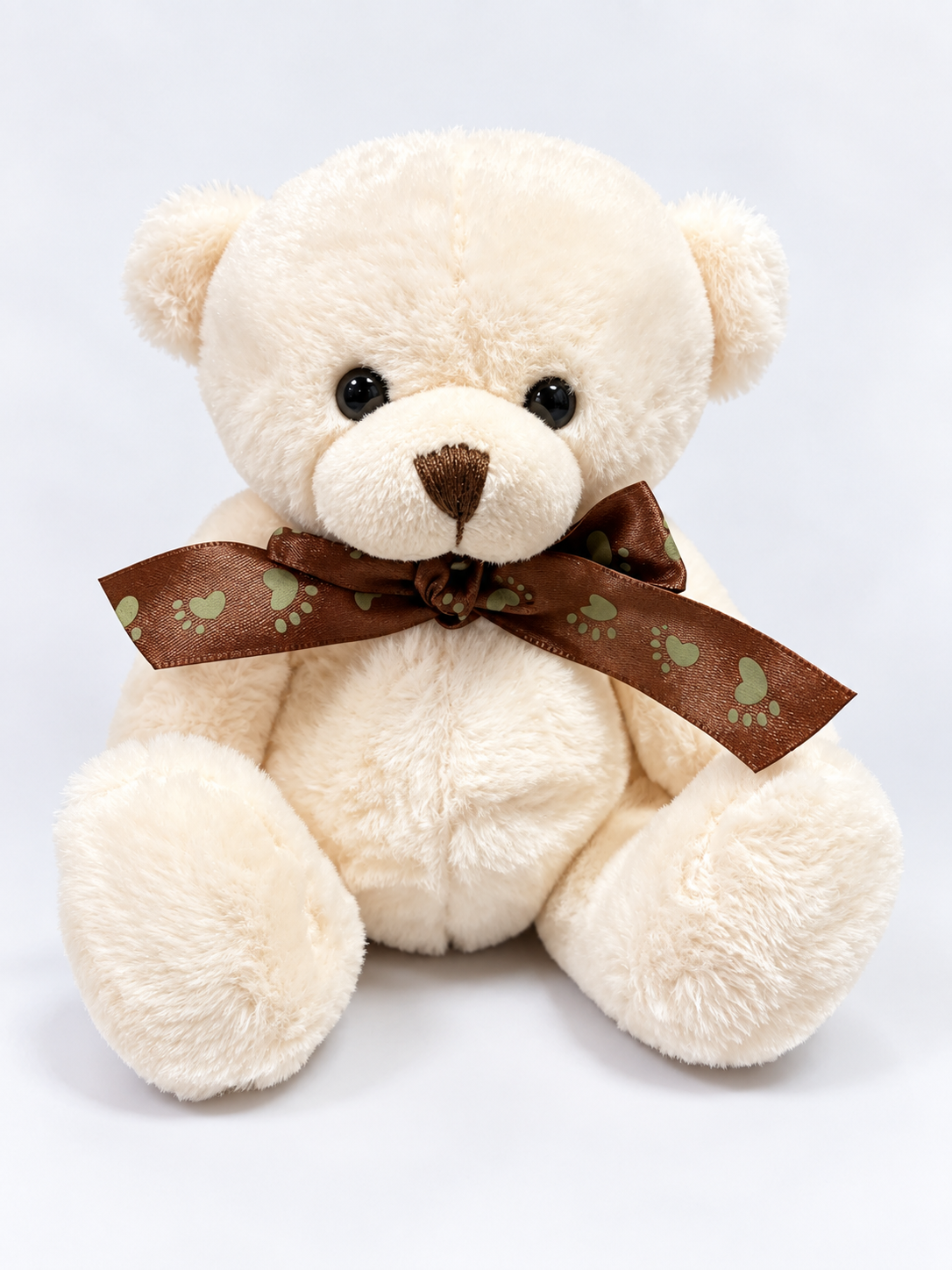 Cream teddy bear with a brown heart-print ribbon bow