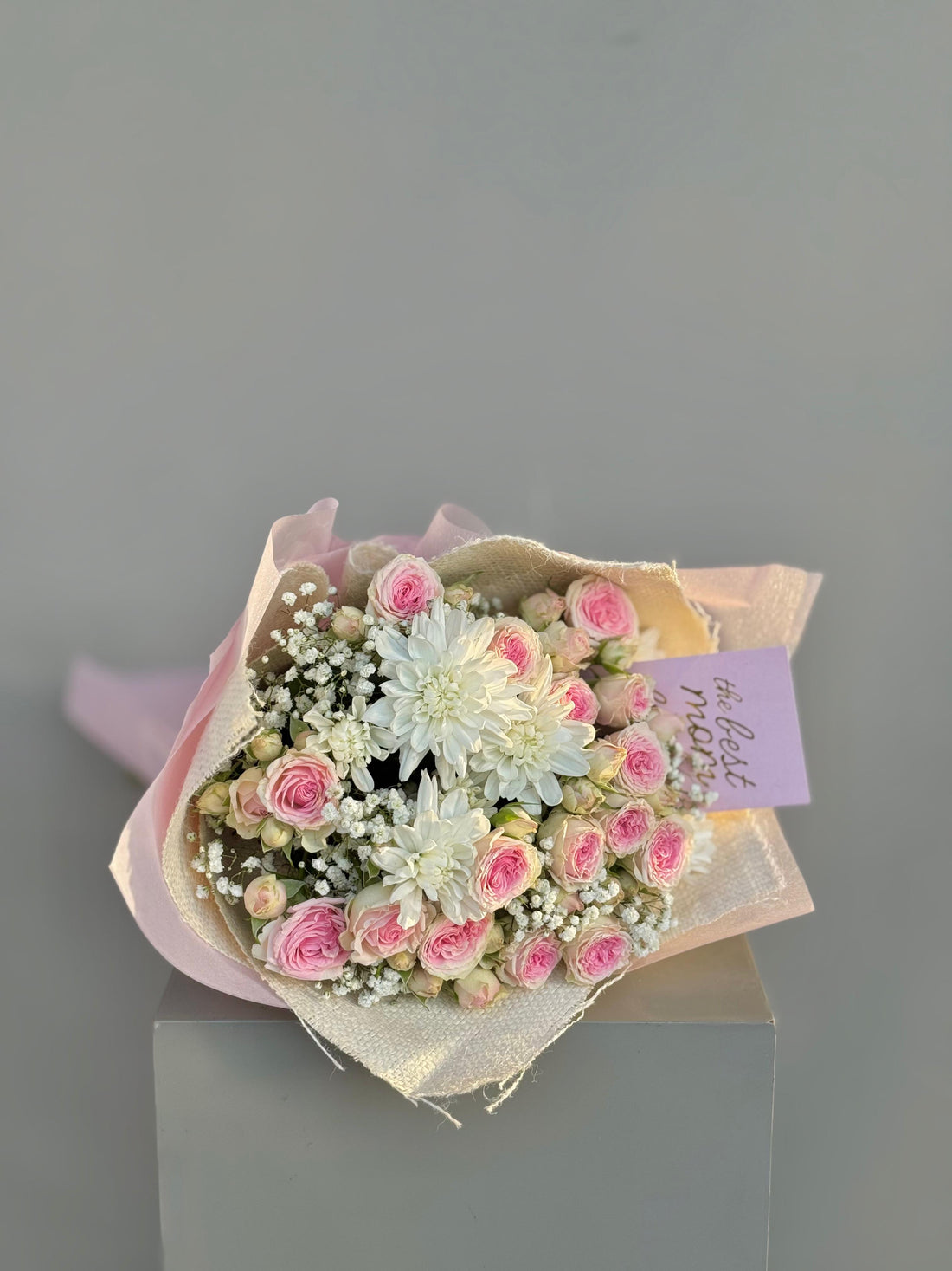 Bouquet of pink and white flowers with a card on a gray background