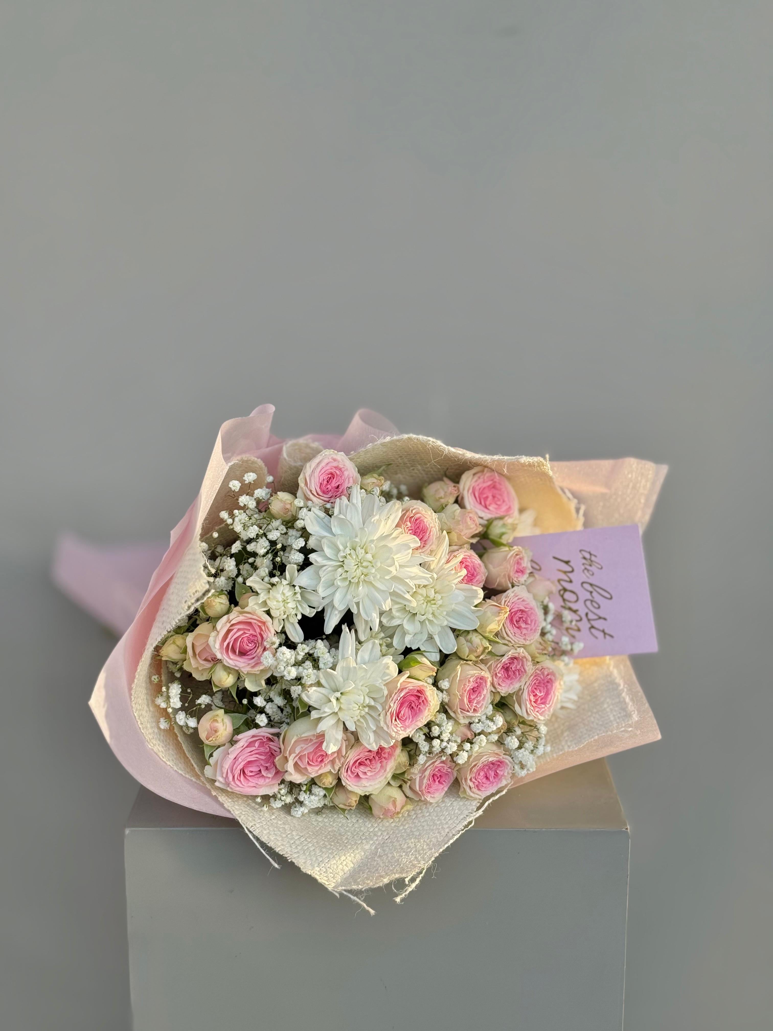 Bouquet of pink and white flowers with a card on a gray background