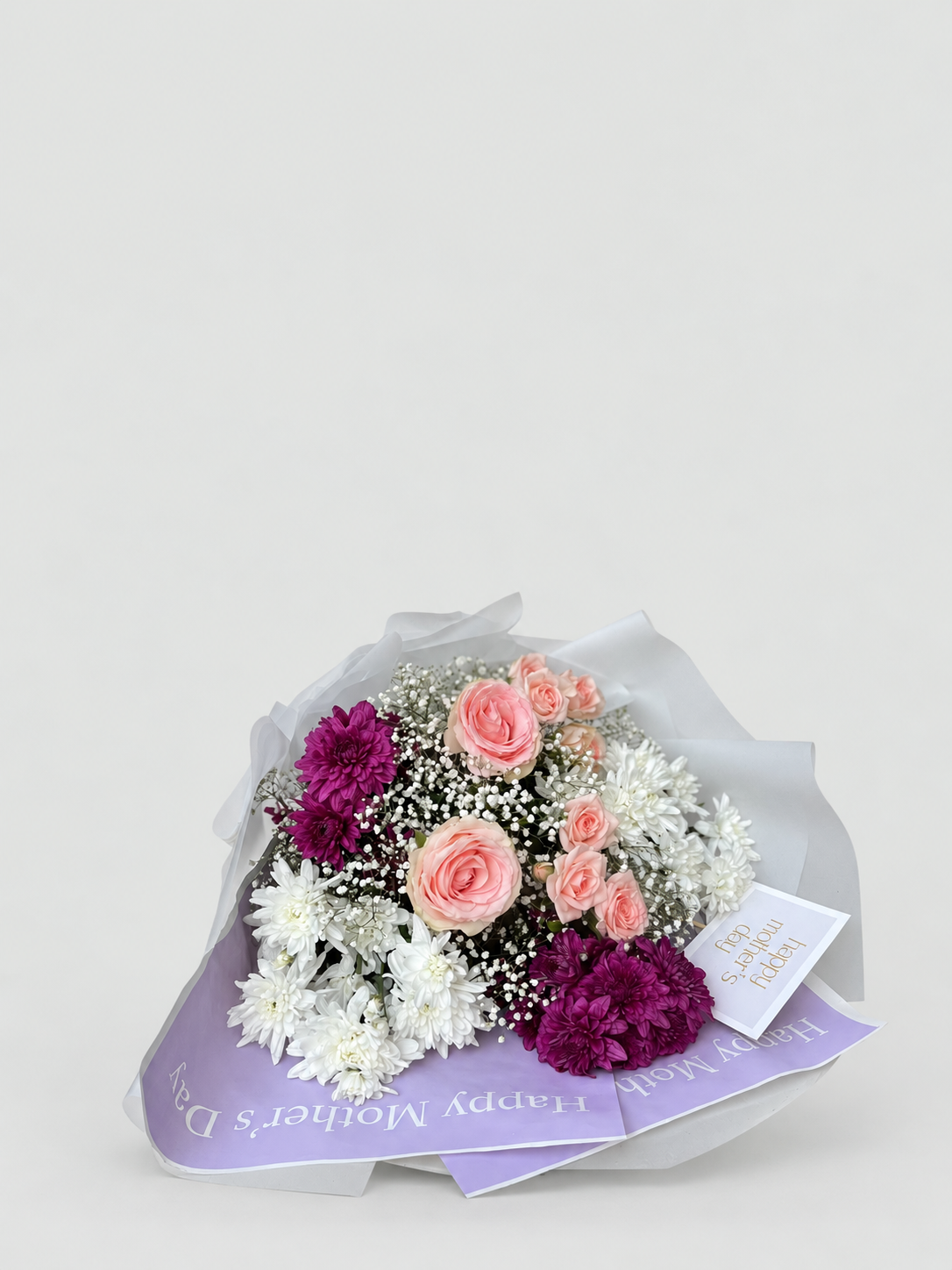 A bouquet of maroon chrysanthemums, white chrysanthemums , roses and spray roses.