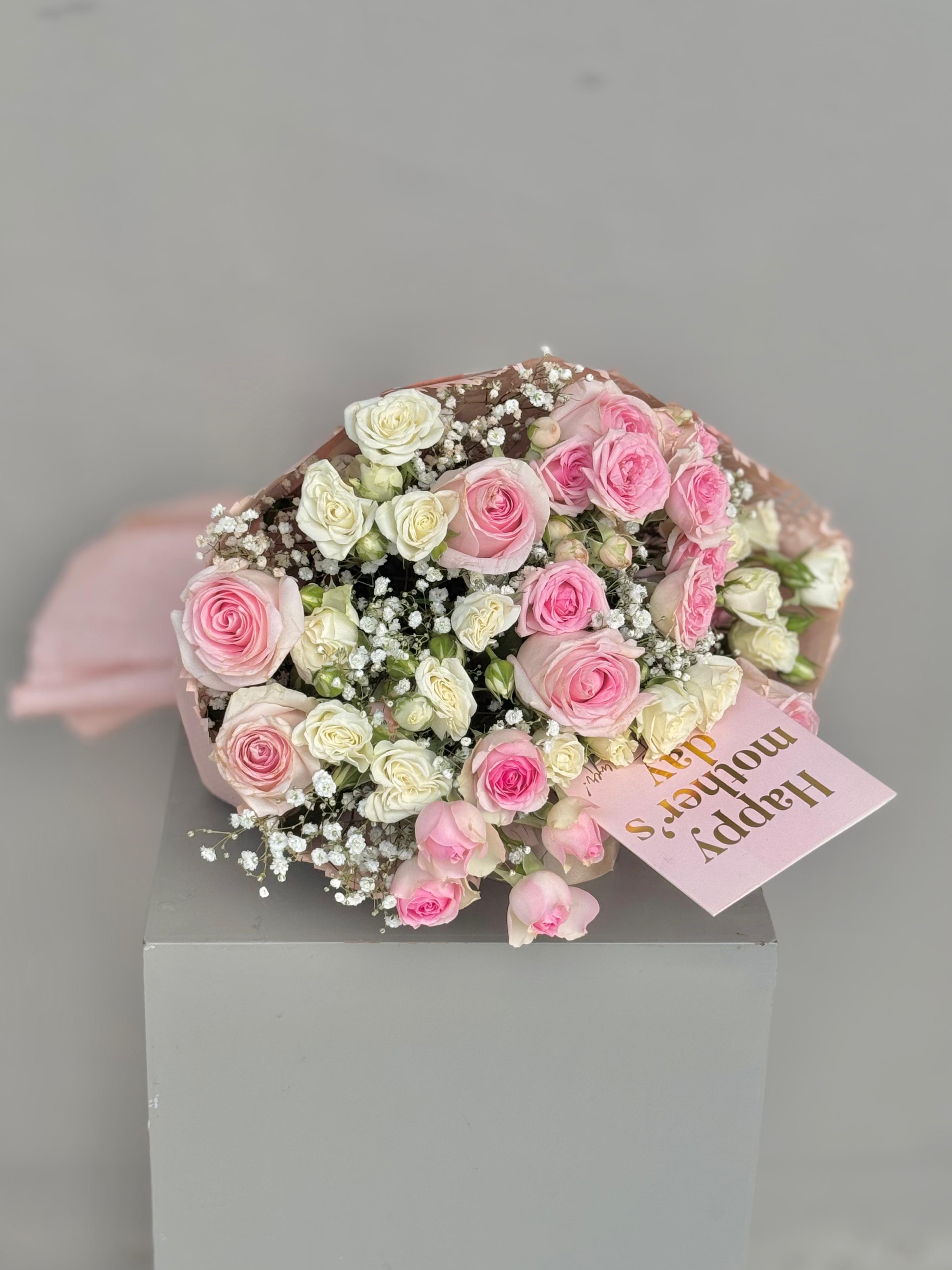 Bouquet of pink and white roses with a card on a gray background