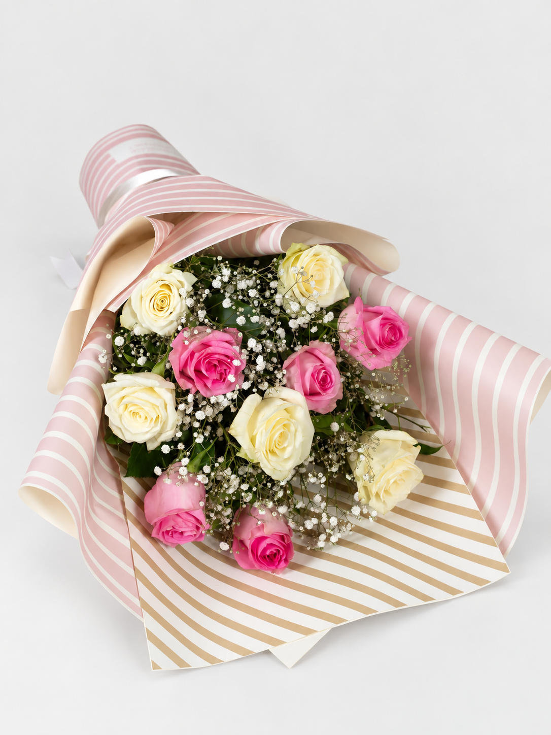 A bouquet of 12 roses, featuring alternating pink and cream-white roses with green foliage and baby&