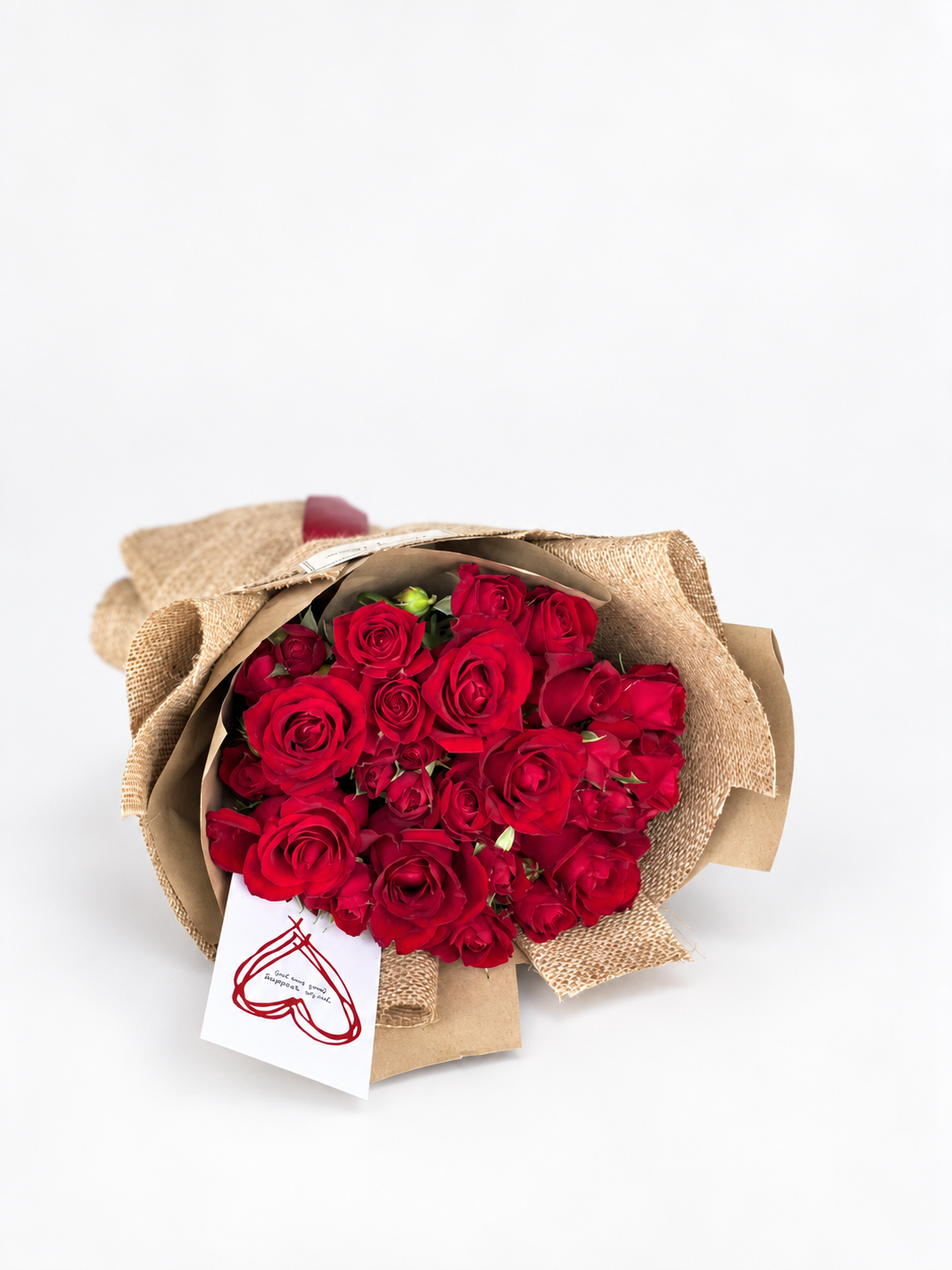 Forbidden Rose bouquet of red roses wrapped in beige burlap paper with a red ribbon and a heart-drawn card