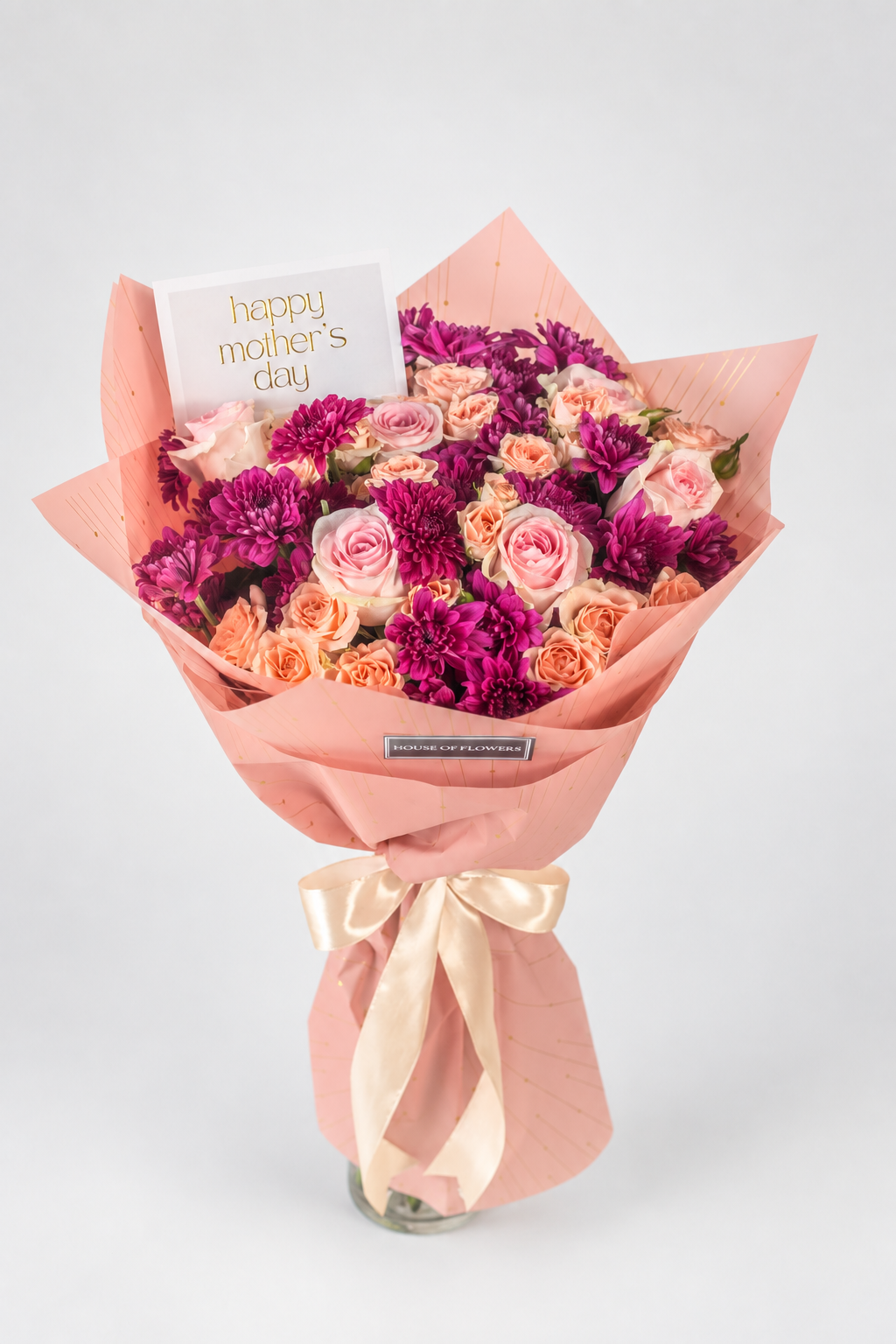 A vibrant bouquet of roses and carnations wrapped in peach paper with a satin ribbon, featuring a &