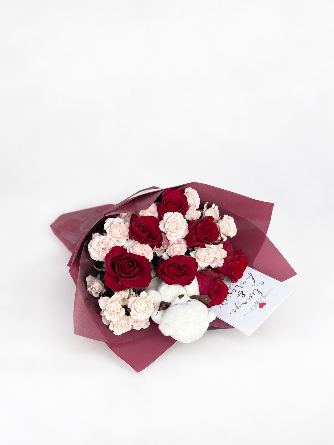 Rosette Etude bouquet of red roses and pink spray roses with a white teddy bear, wrapped in maroon paper with a heart card
