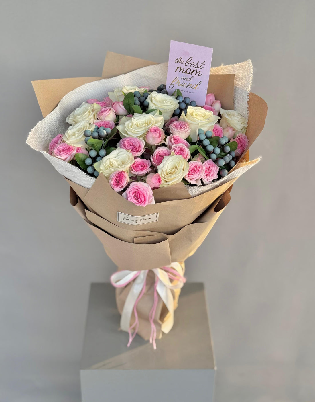 Bouquet of flowers wrapped in brown paper with a card on a gray background