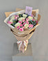 Bouquet of flowers wrapped in brown paper with a card on a gray background