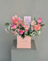Peach Symphony arrangement with peach, pink and coral roses and gypsophila in a pink box, with a "Best Mom Ever" card