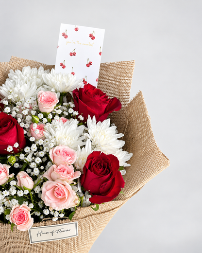 Close-up of the Cherry Blossom bouquet with red and peach roses, chrysanthemums and a cherry-print card