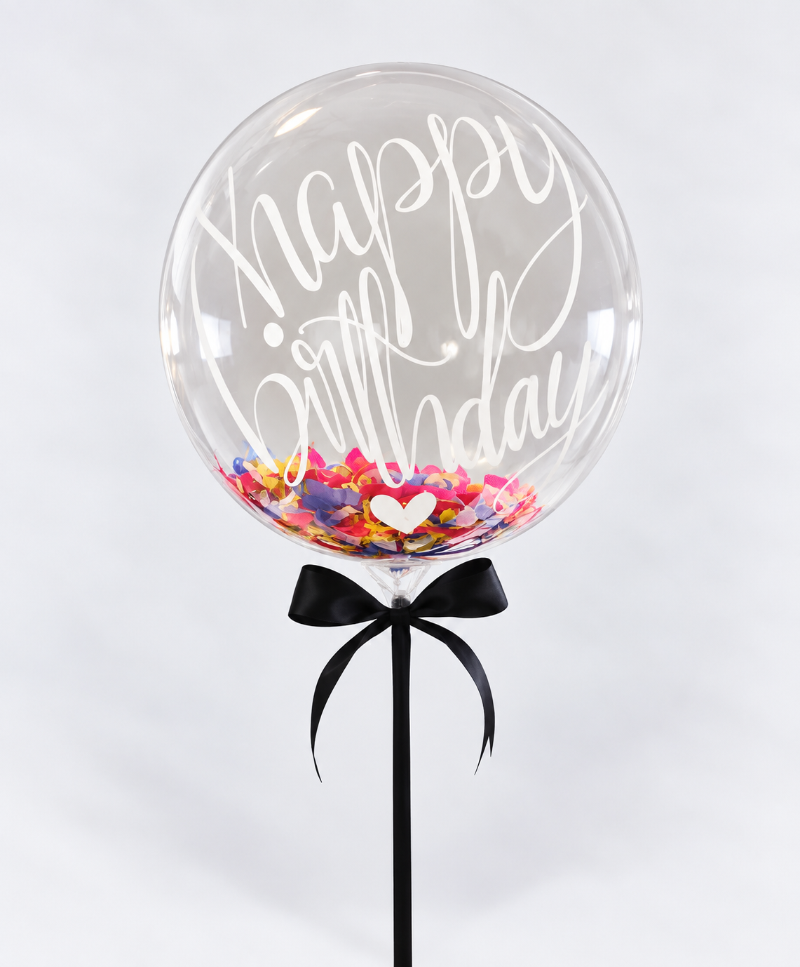 Clear confetti balloon reading Happy Birthday with rainbow confetti and a black ribbon