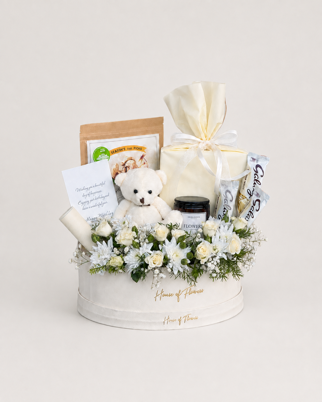 Creamsicle Charm white round box with white roses and chrysanthemums, a white teddy bear, gourmet snacks and a wrapped cream gift box