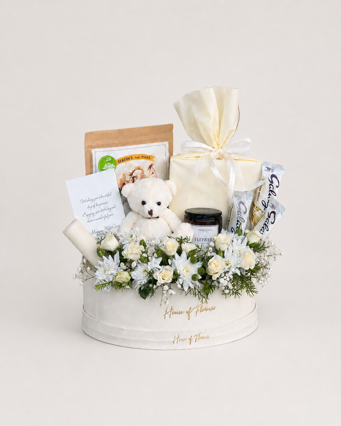 Creamsicle Charm white round box with white roses and chrysanthemums, a white teddy bear, gourmet snacks and a wrapped cream gift box