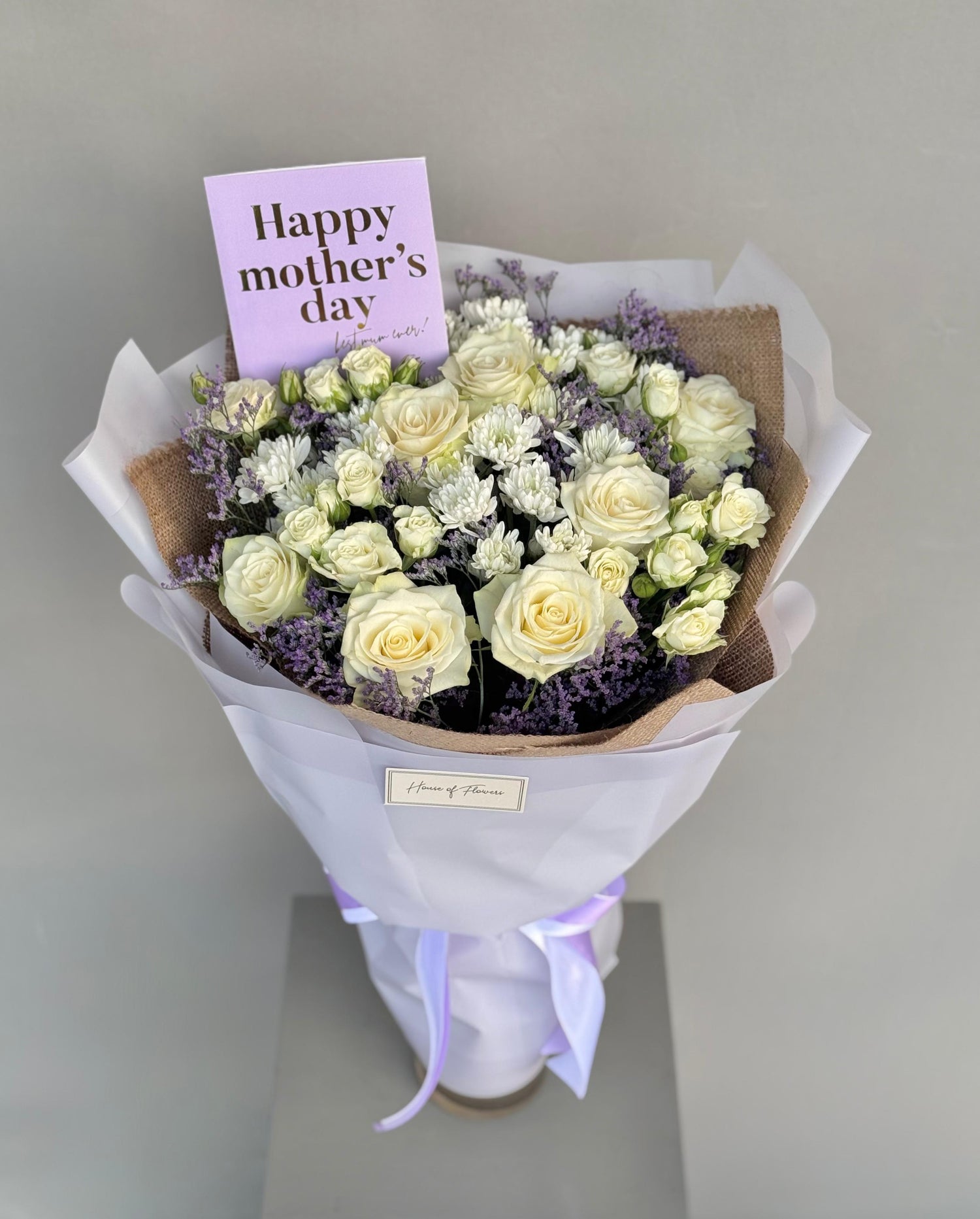 Whispers of Love bouquet with cream roses, lavender and white chrysanthemums, wrapped in kraft and white paper with a "Happy Mother&