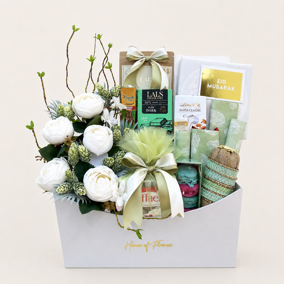 An elegant gift basket from House of Flavor, filled with an assortment of gourmet treats, soaps, and a floral arrangement of white roses and greenery, presented on a light beige background.
