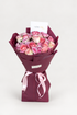 Rosie Rhapsody bouquet of pink, cream, and blush roses wrapped in maroon paper with a pink ribbon and card