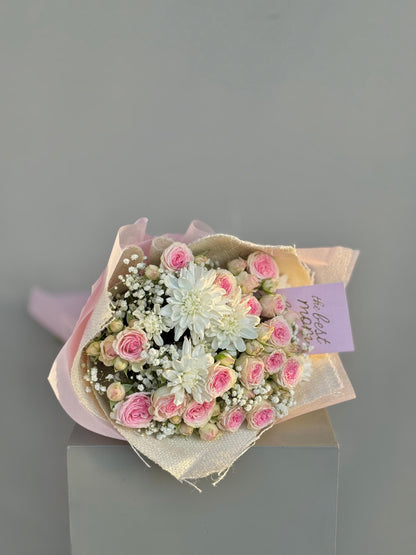 Bouquet of pink and white flowers with a card on a gray background