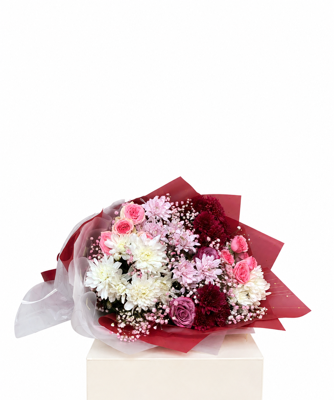 A bouquet of mixed flowers including pink roses, white chrysanthemums, burgundy carnations, and baby&
