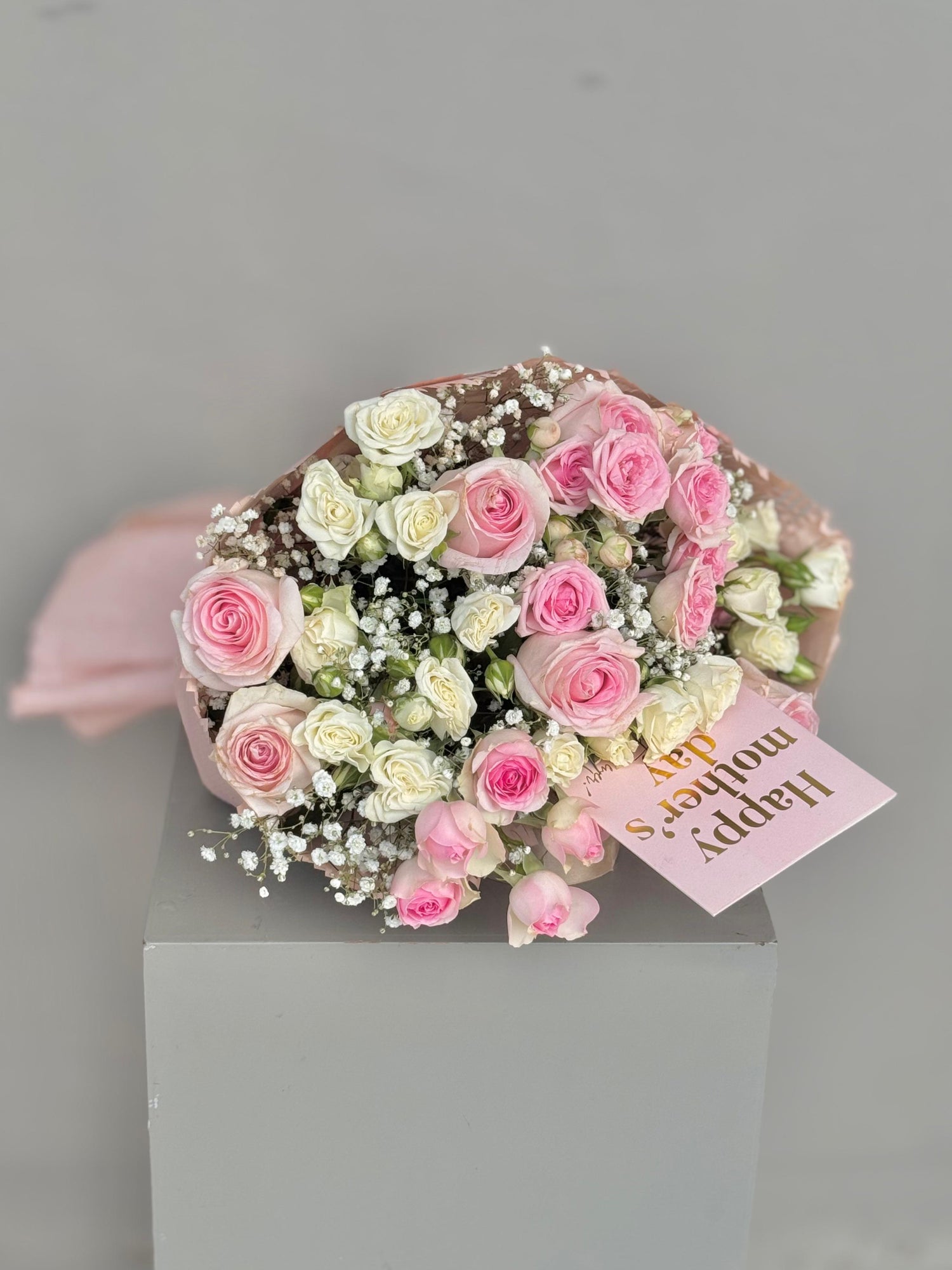 Bouquet of pink and white roses with a card on a gray background