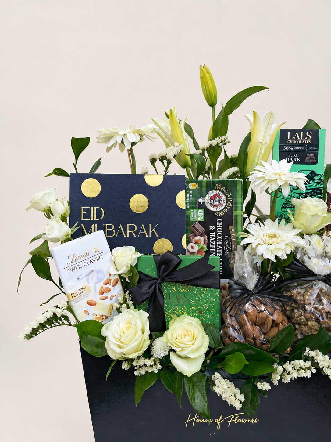 House of Flowers Eid Bliss Box with Lindt Swiss Classic, Lals Pure Dark Chocolate, MacAndrews Chocolate Chip &amp; Hazelnut Cookies, Galaxy chocolates, mixed nuts, white lilies, gerberas, spray roses and gypsophila in a black branded box