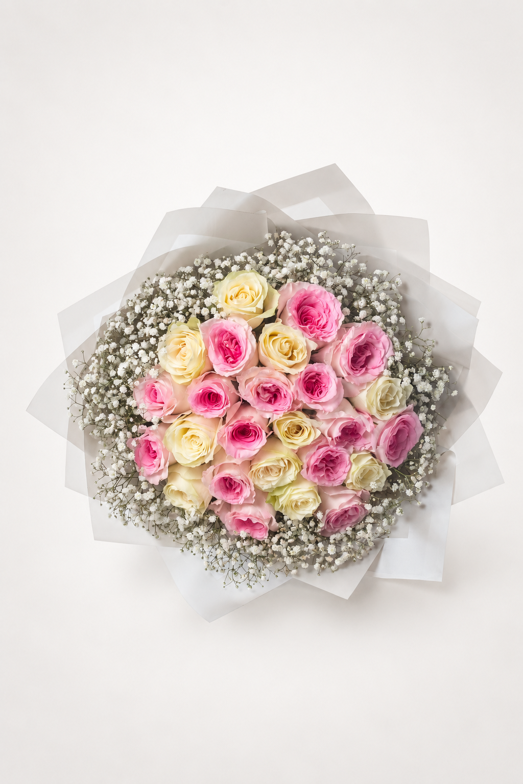 A round bouquet of pink and cream roses with white baby&