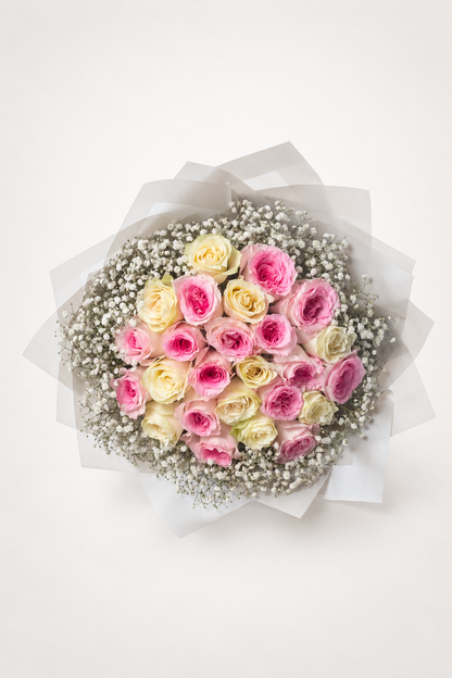 A round bouquet of pink and cream roses with white baby&