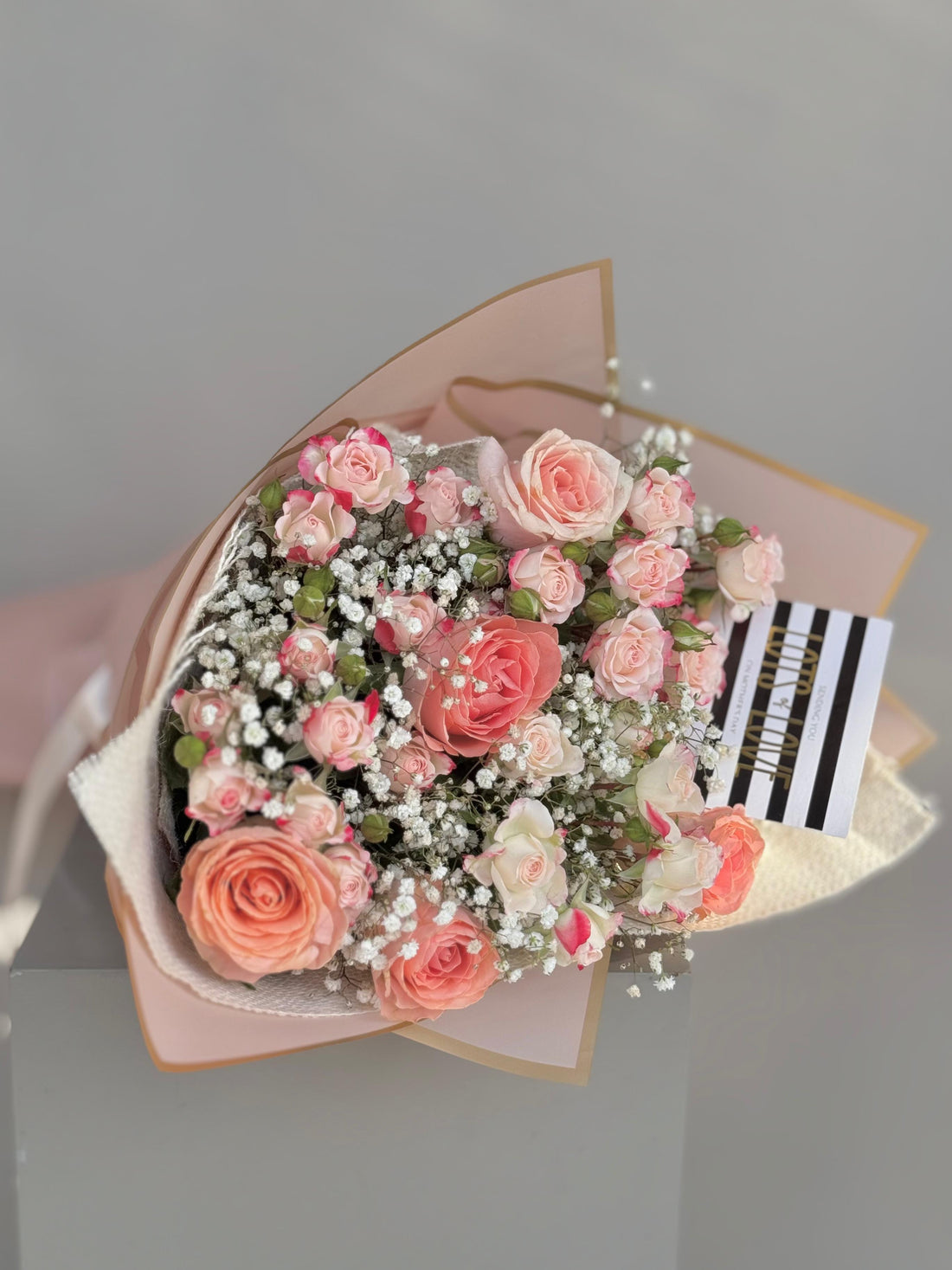 Bouquet of pink flowers with a striped card on a gray background