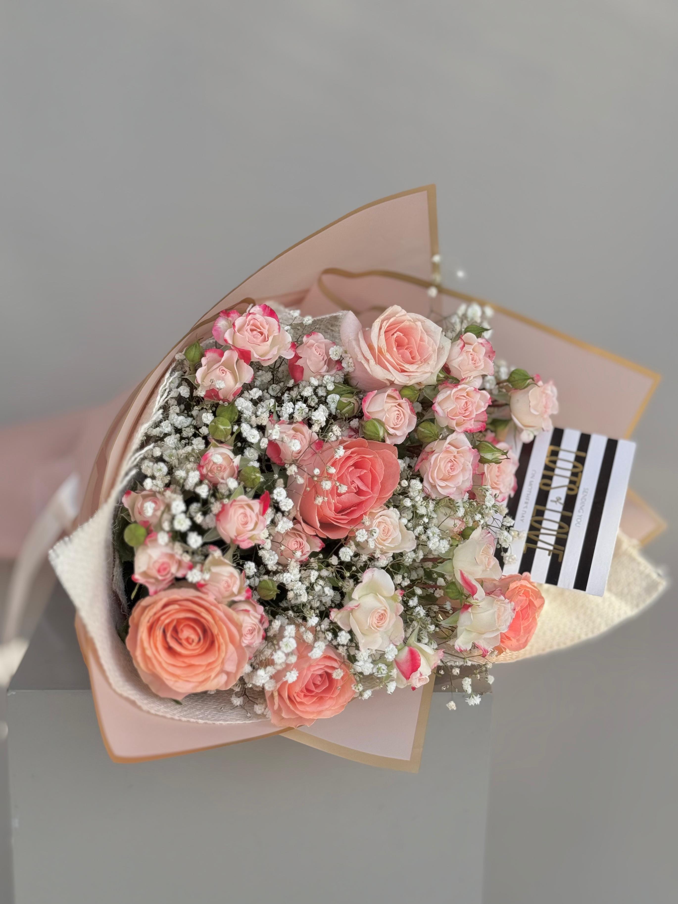 Bouquet of pink flowers with a striped card on a gray background