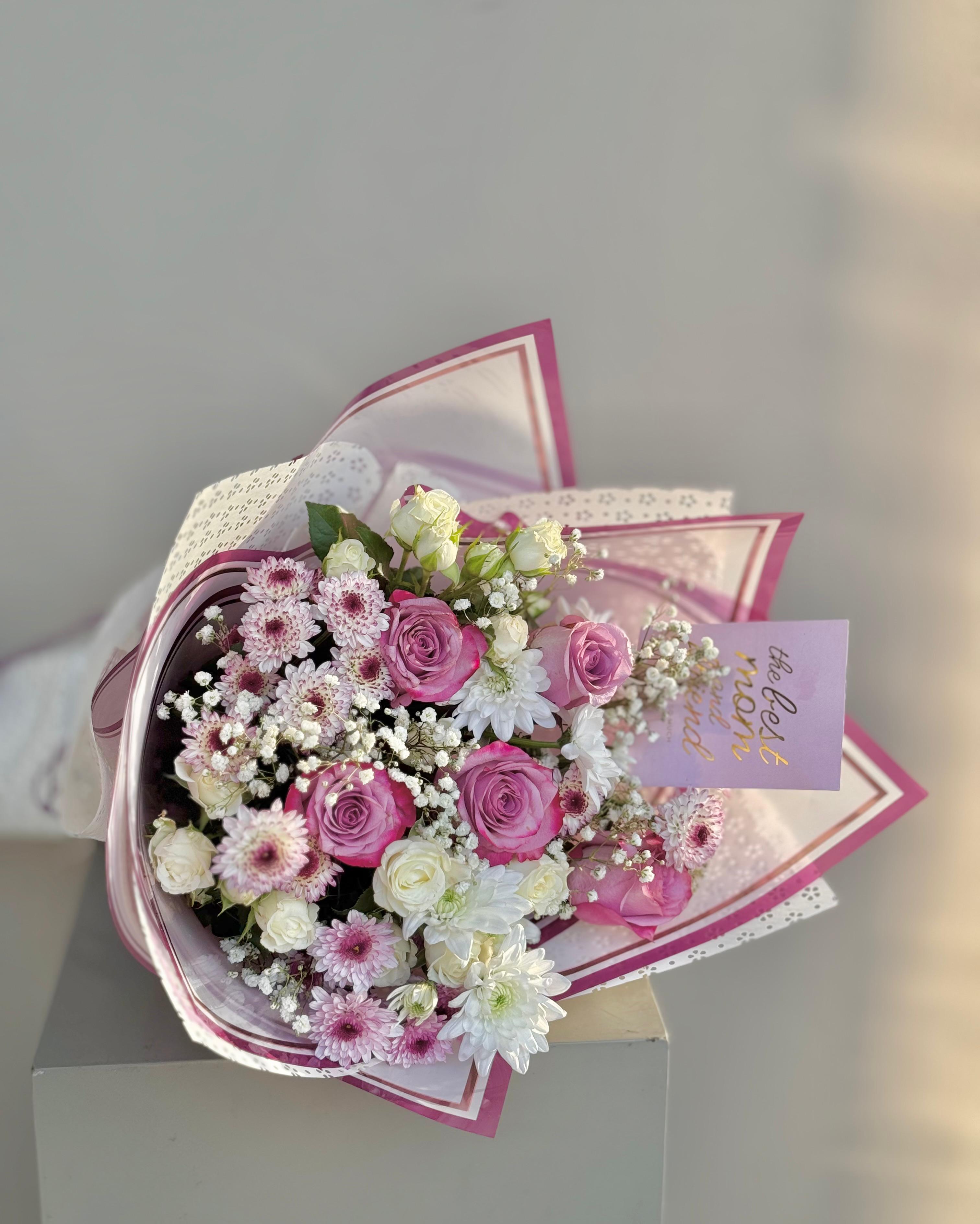 Bouquet of pink and white flowers with a decorative paper wrap on a light gray background