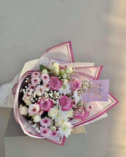 Bouquet of pink and white flowers with a decorative paper wrap on a light gray background