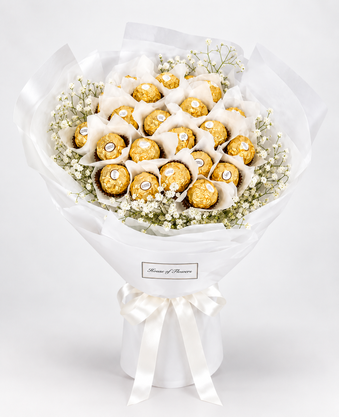 A gift bouquet made of assorted Ferrero Rocher chocolates wrapped in white tissue paper and a white paper sleeve, tied with a white ribbon.