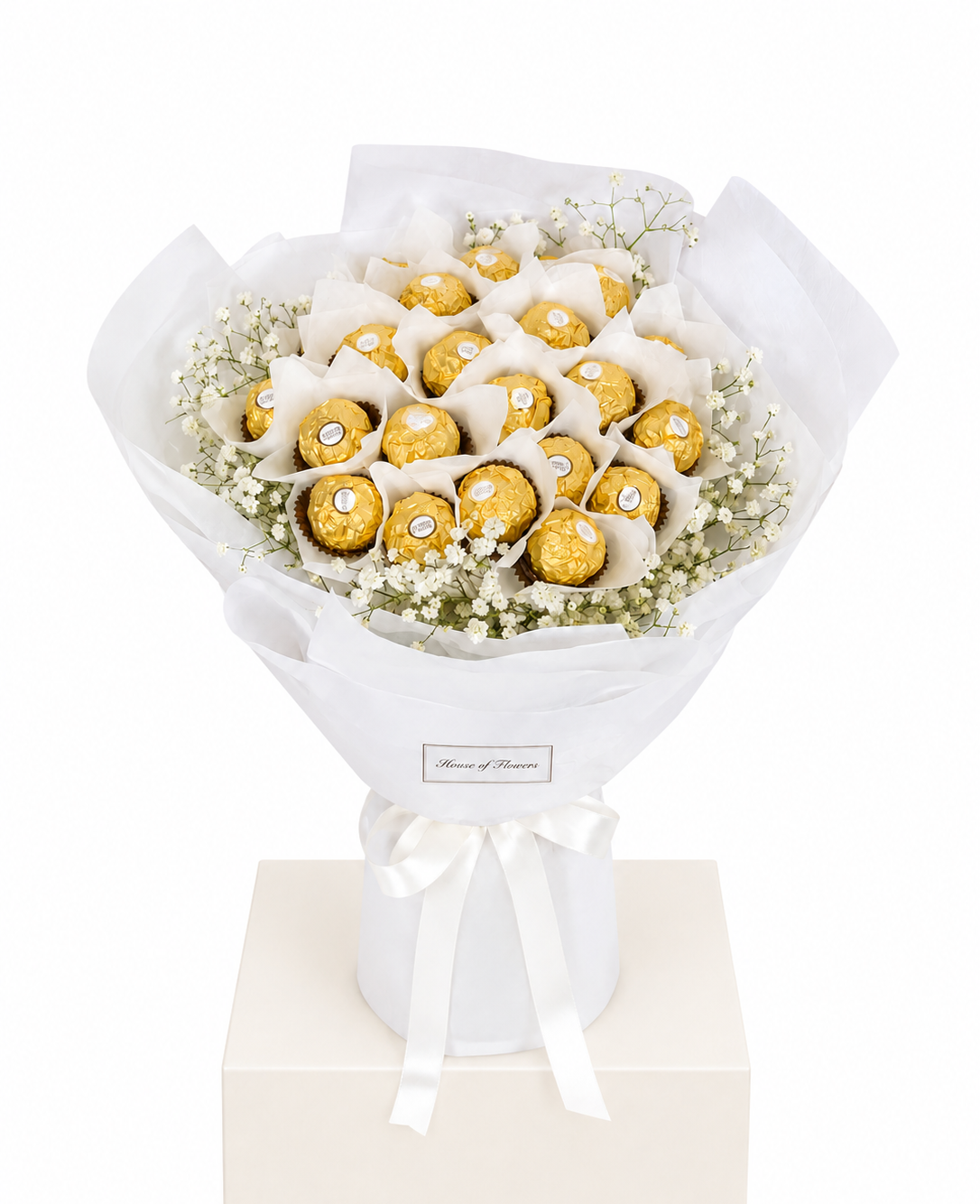 A gift bouquet made of assorted Ferrero Rocher chocolates wrapped in white tissue paper and a white paper sleeve, tied with a white ribbon.