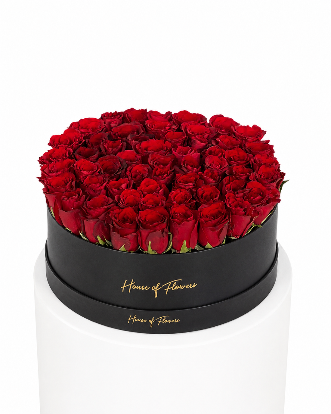 A round arrangement of deep red roses in a black cylindrical box with gold &