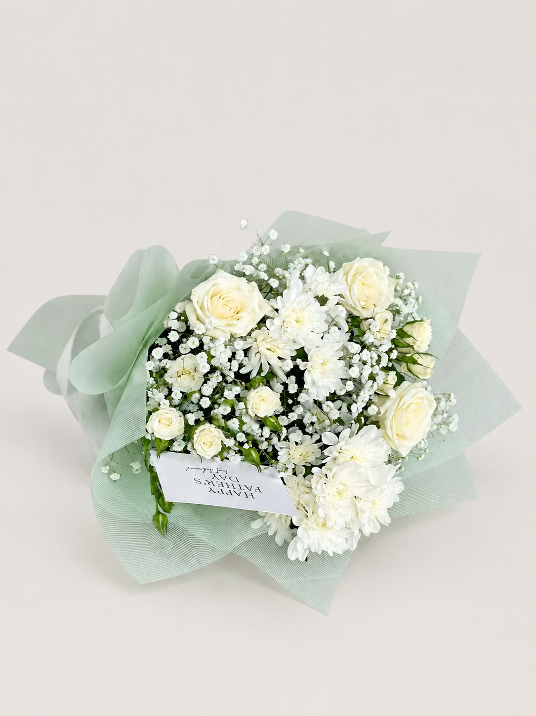 Legacy in Bloom white bouquet with roses, chrysanthemums, spray roses, baby’s breath, and a greeting card
