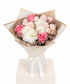 A floral bouquet with pink and white flowers wrapped in beige paper and a white ribbon, displayed on a cream-colored gift box against a white background.