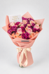A vibrant bouquet of roses and carnations wrapped in peach paper with a satin ribbon, featuring a &