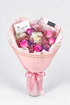 A bouquet of flowers including roses and chrysanthemums in purple, pink, and white colors, with a pink veil wrapped around the stems, tied with a pink ribbon.