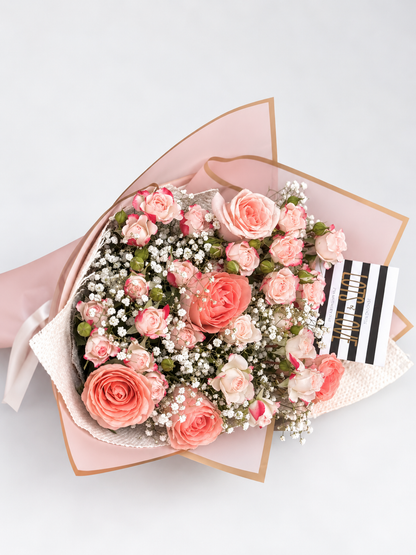 Bouquet of pink flowers wrapped in pink paper with a gray background