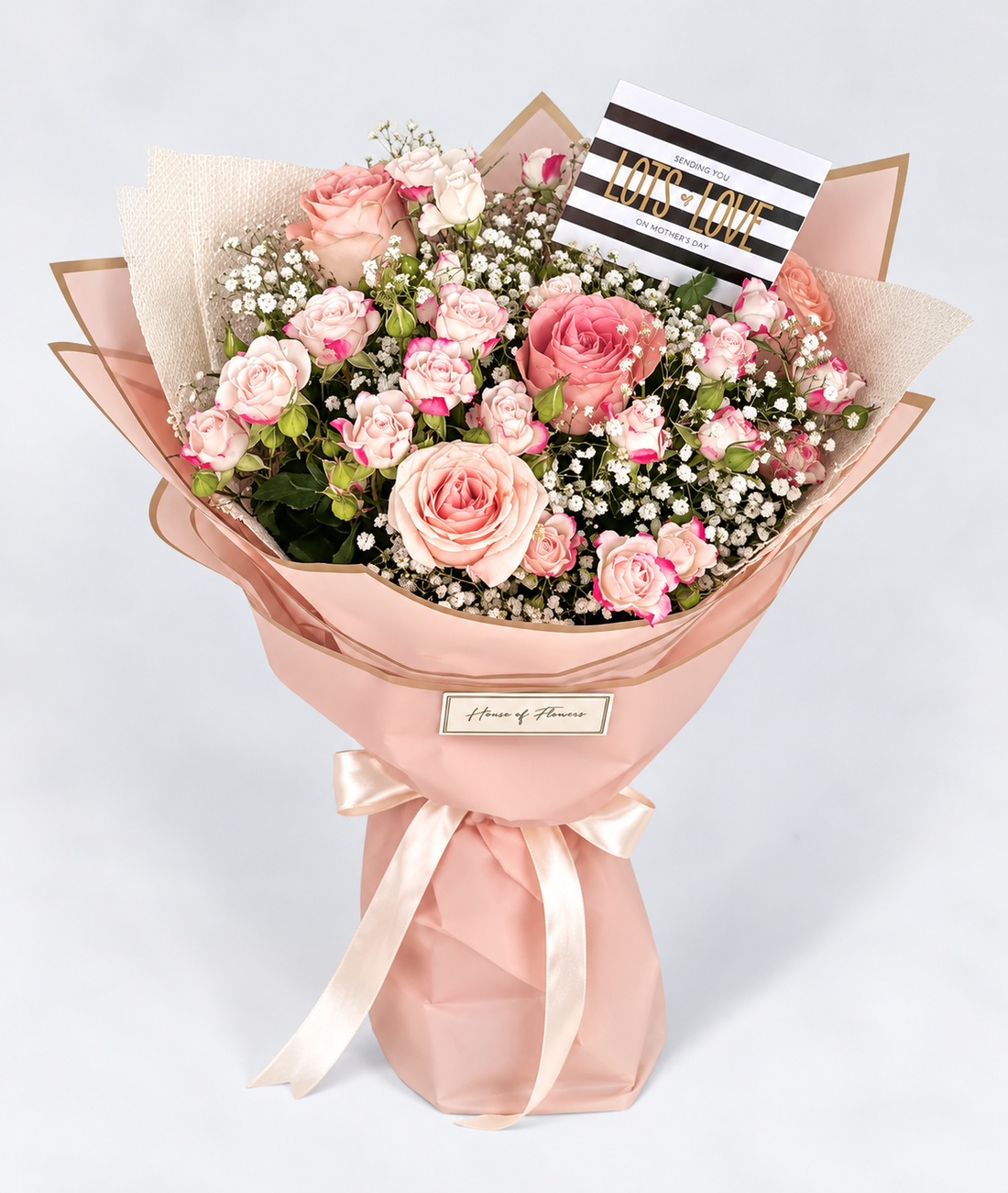 Bouquet of pink flowers wrapped in pink paper with a gray background