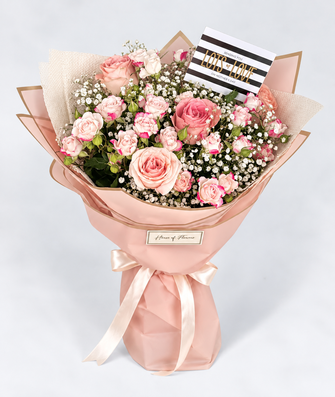 Bouquet of pink flowers wrapped in pink paper with a gray background