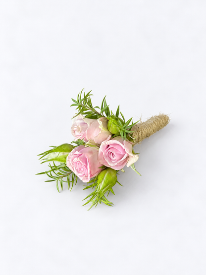 Pink spray rose boutonniere with greenery and a twine-wrapped stem