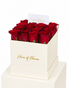 A premium gift box of red roses from House of Flowers, featuring a stack of two cream-colored square boxes with gold foil branding, filled with vibrant red roses and topped with a white card that reads &