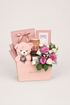 Rosy Plum gift box with pink and purple roses, a teddy bear, chocolates, and a candle in a blush pink box.