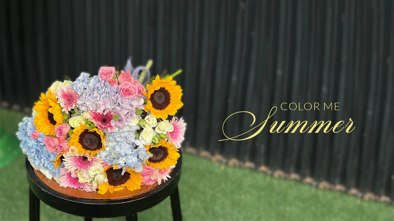 Colorful bouquet of flowers on a stool with 'Color Me Summer' text against a black background.