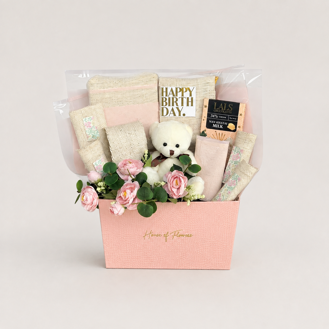 A baby shower gift basket from House of Flowers, featuring a pink box filled with baby wipes, a teddy bear, pink roses, and a &