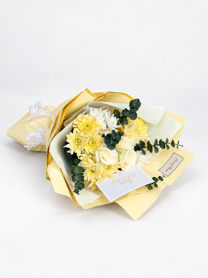 Warmth of You bouquet with cream and white chrysanthemums and eucalyptus, wrapped in soft yellow paper with greeting cards